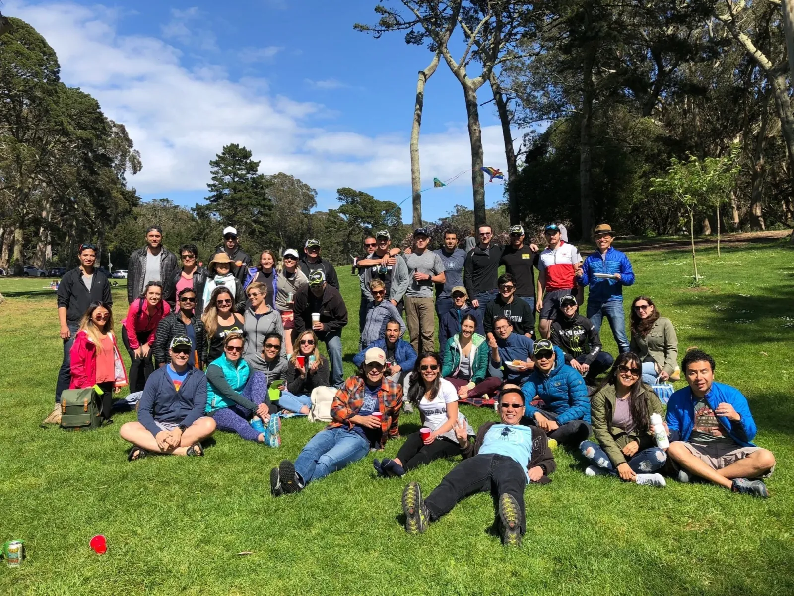 Dozens of SF Tri Club members gathered on the grass at a sunny park picnic