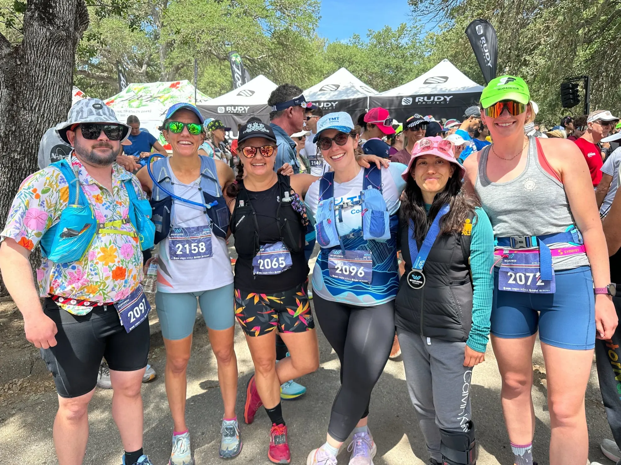 Six SF Tri Club members in running kit and race bibs with their arms around each other at the Wildflower race.